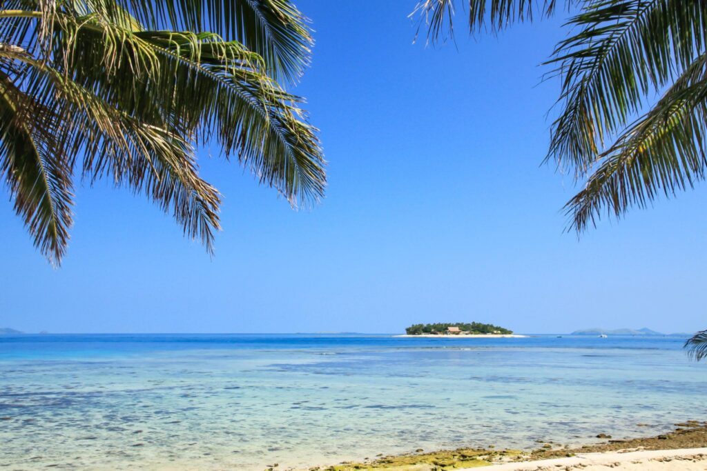 Remote tropical island surrounded by crystal clear waters on a sunny day in Fiji.