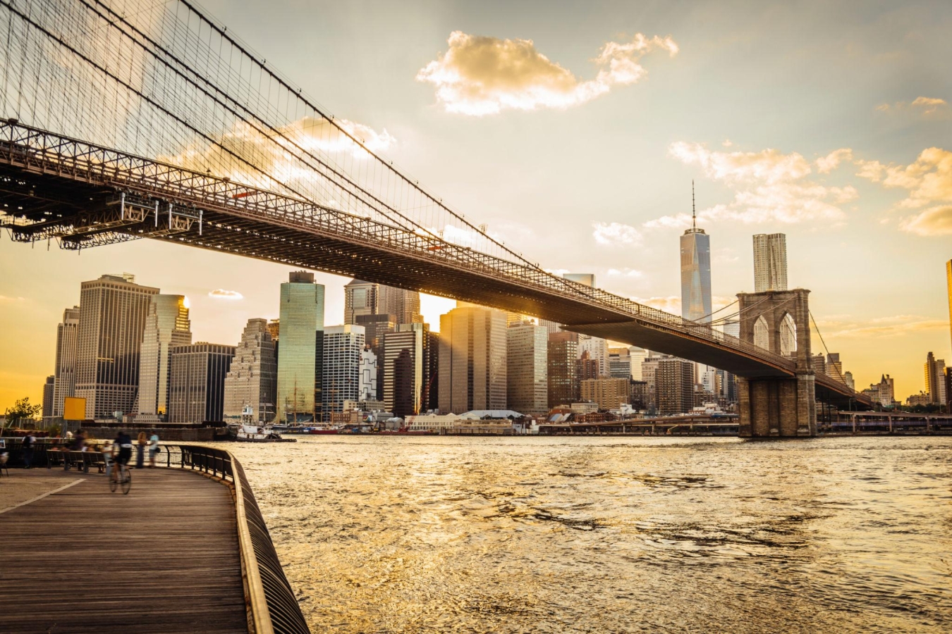 A scenic view of the Brooklyn Bridge and the Lower Manhattan skyline at sunset.