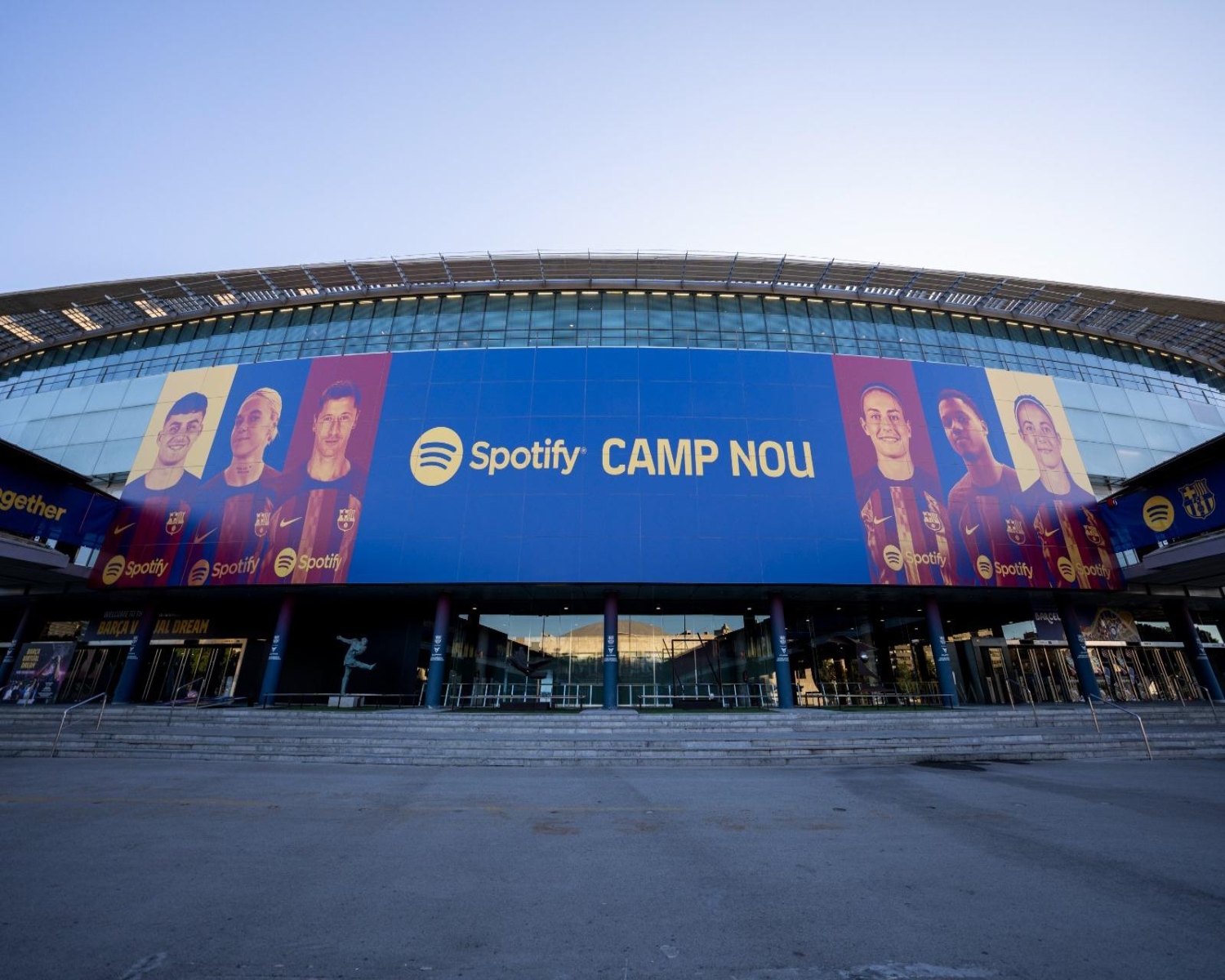 The facade of the Spotify Camp Nou Stadium in Barcelona, featuring a large mural of FC Barcelona players.