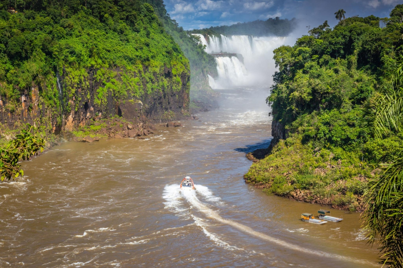 A speed boat navigating the Iguazu River towards the Iguazu Falls, located on the border between Argentina and Brazil.