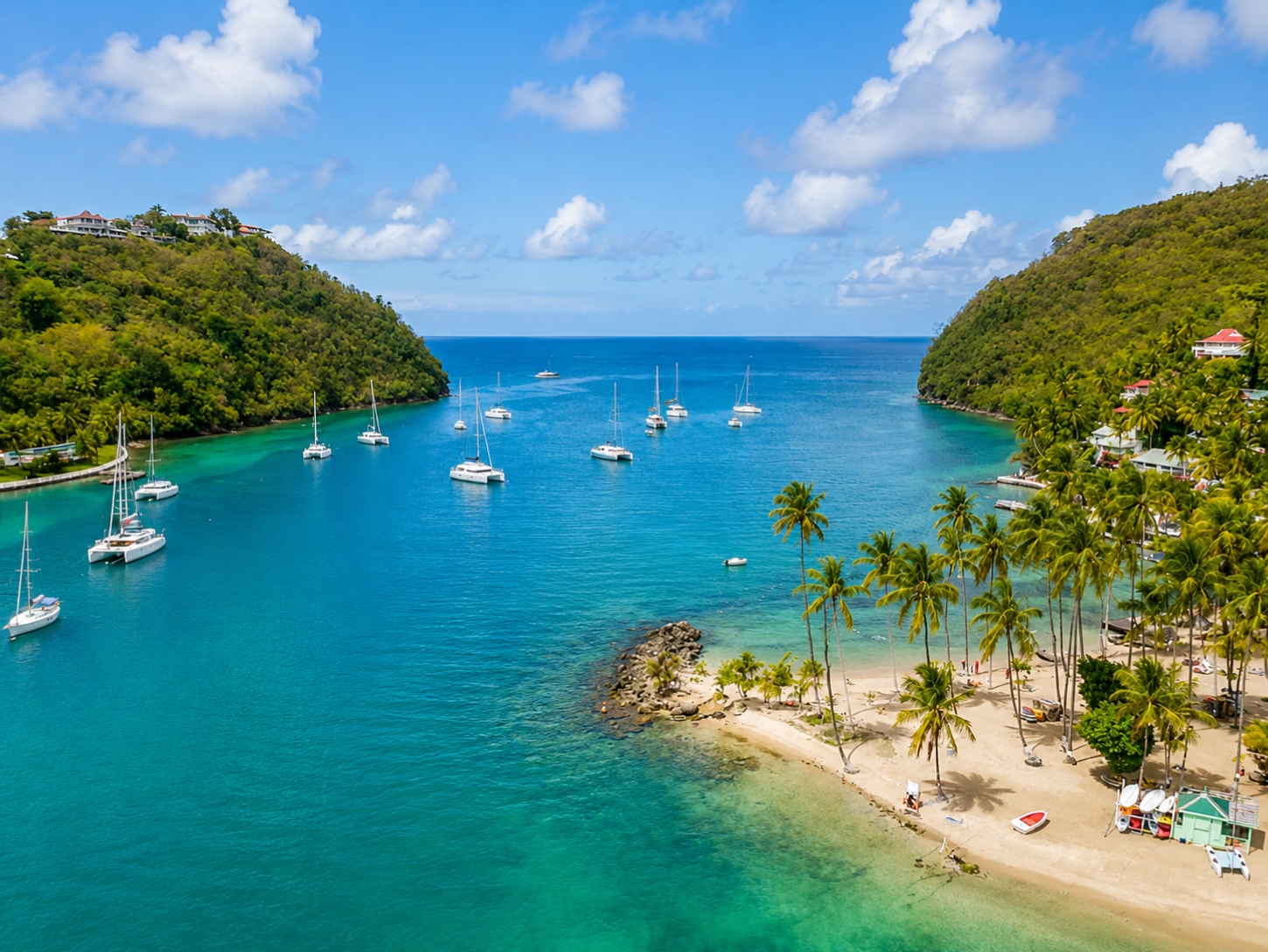 The lush, palm-fringed coastline and anchored yachts of Marigot Bay in St. Lucia.
