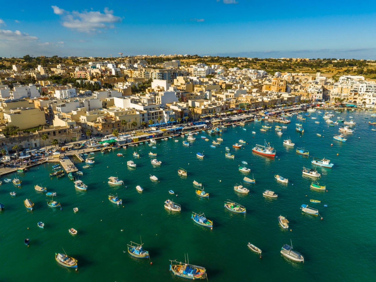The harbor at Marsaxlokk Fishing Village in southeastern Malta is filled with numerous luzzu boats, traditional Maltese fishing boats known for their bright colors.
