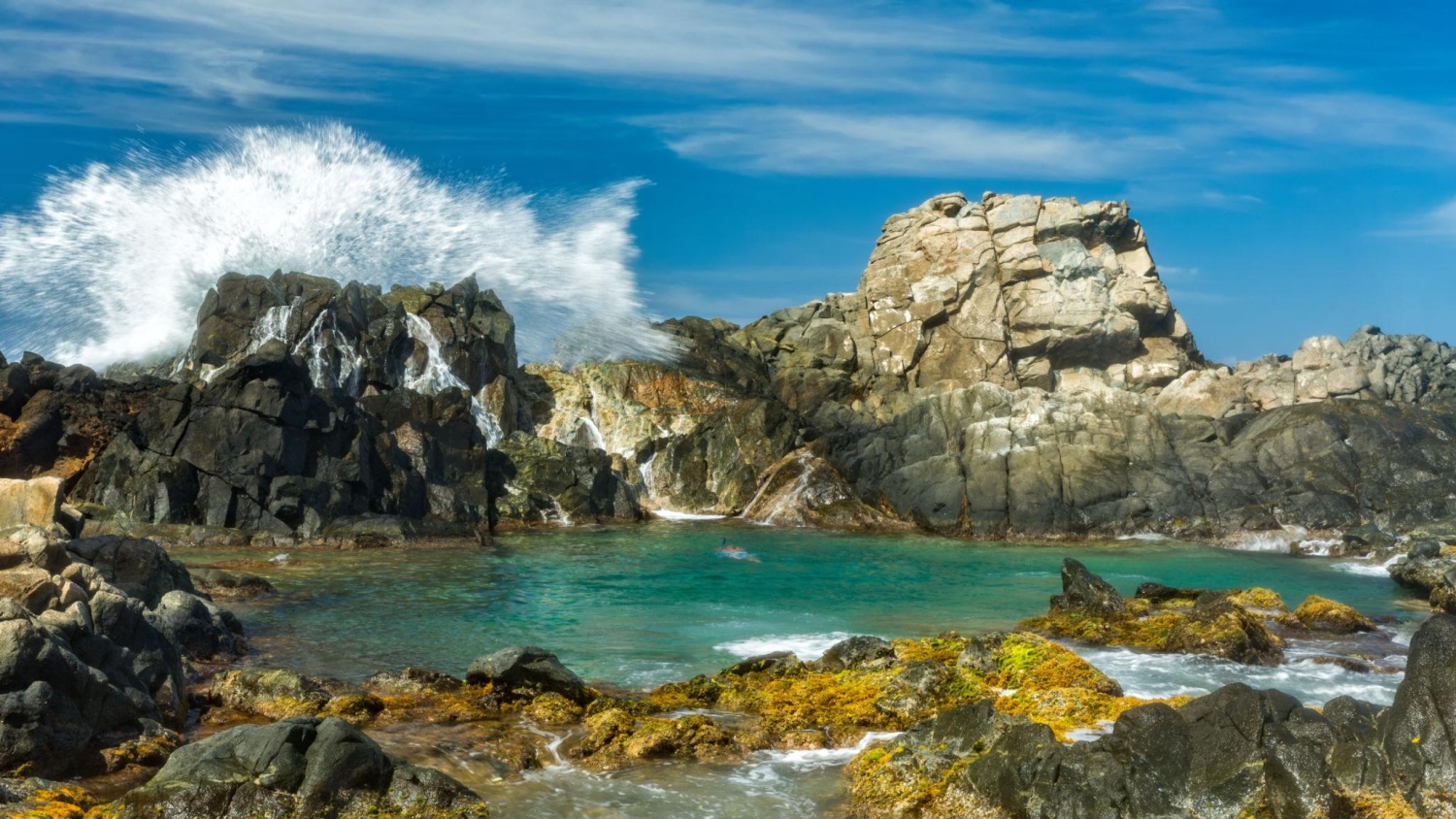 Conchi Natural Pool, a secluded swimming spot shielded from ocean waves by rugged volcanic rock formations, is a popular tourist attraction located within Aruba's Arikok National Park.