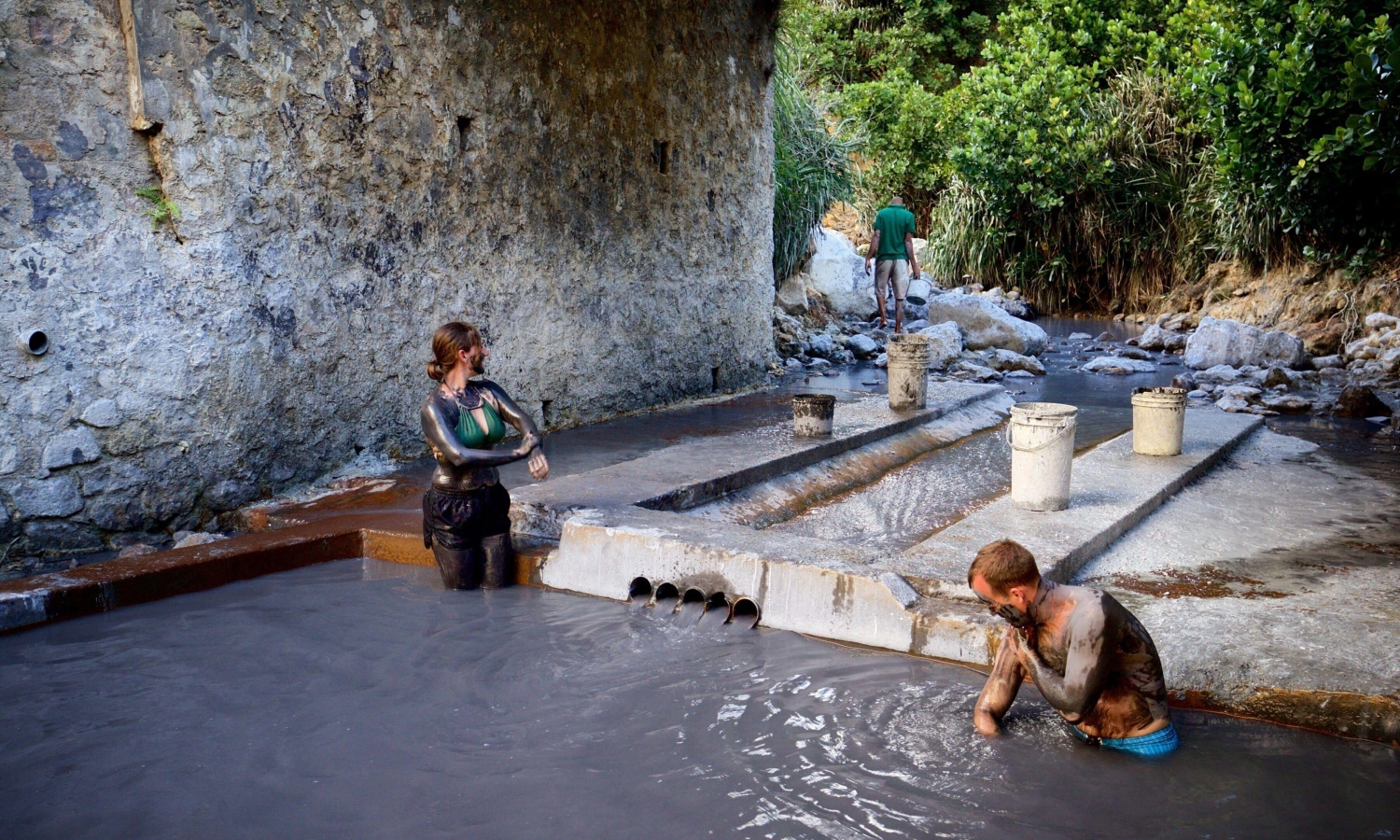 Visitors enjoying the rejuvenating mineral-rich mud baths at the Sulphur Springs, the most active geothermal area in the Lesser Antilles, featuring sulfur springs, steam vents and boiling mud pools in Soufrière, Saint Lucia.