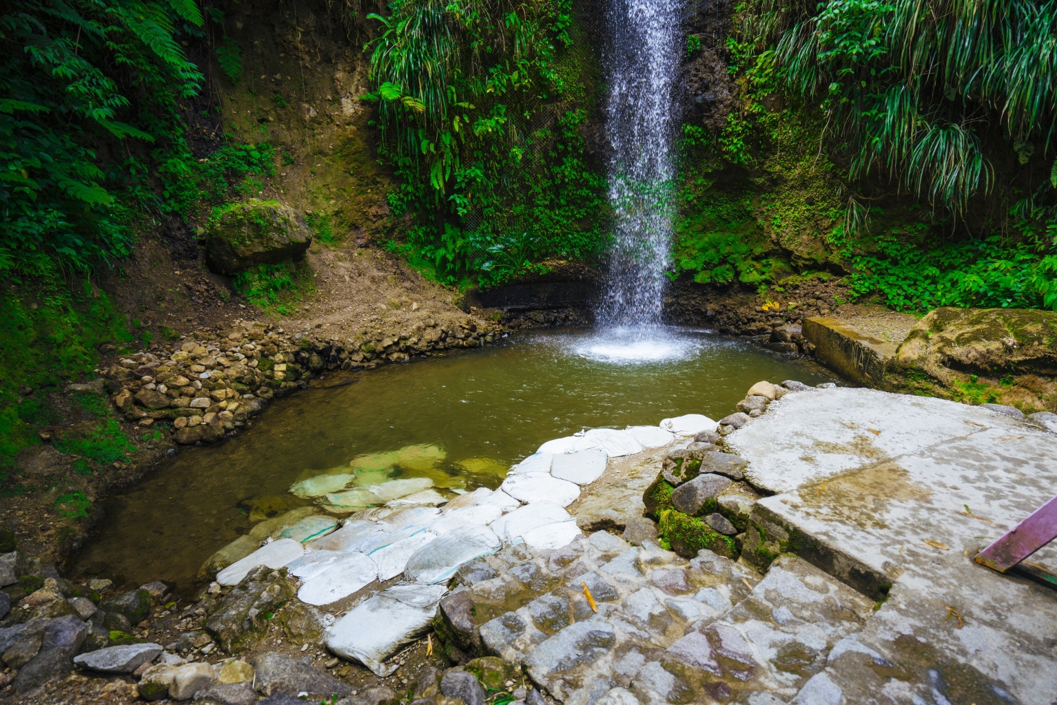 Toraille Waterfall is a popular 50 foot natural wonder located in Soufrière, Saint Lucia featuring a swimmable watering hole and is surrounded by a lush tropical rainforest setting.